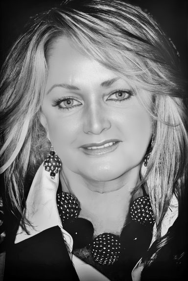 Portrait of a woman with long light hair, wearing a black and white outfit, smiling.
